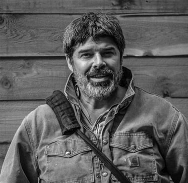 a man with a camera bag in front of a wood plank wall