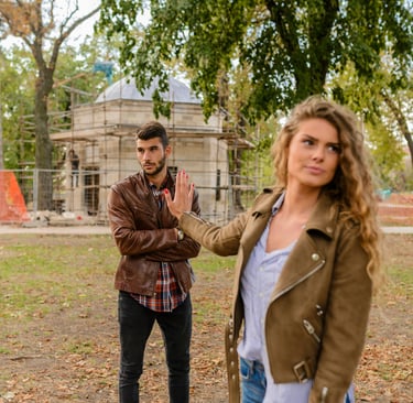 A couple sitting apart, with one partner looking distressed while the other avoids eye contact, symb