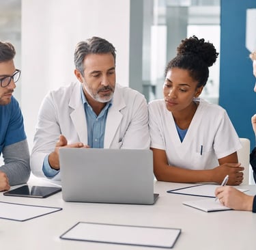 Équipe pluridisciplinaire hospitalière préparant le référentiel HAS 2027 autour d’un ordinateur