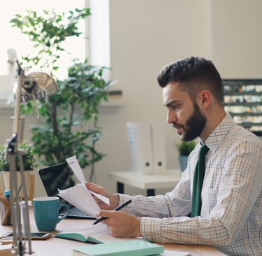 Person using a computer with books, representing cognitive behavioral therapy learning and reflectio