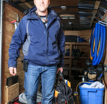 a man in a blue jacket is standing in front of a moving truck