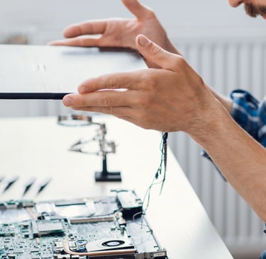 a man holding a tablet computer and pointing at a laptop