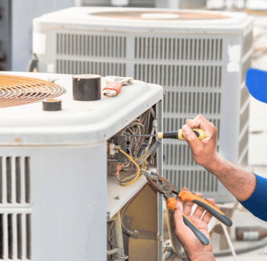 a man in a blue shirt is working on a large air conditioner