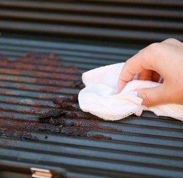 a person cleaning a grill grill with a cloth cloth