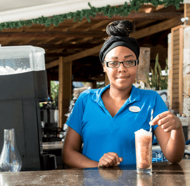 a woman in a blue shirt is holding a drink