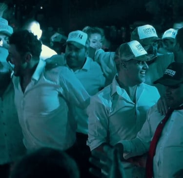 Grupo de hombres festejando y bailando con gorras personalizadas en un evento animado por un DJ