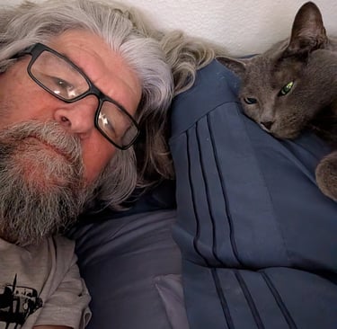 Greg Rowland and his cat, Big Bit laying in bed together.