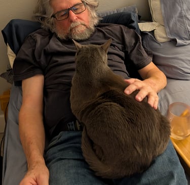 Greg Rowland lying in bed with his cat, big bit