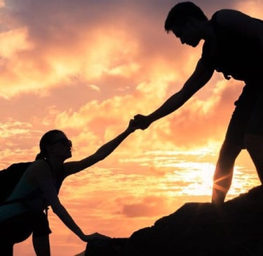 a man helping another man climb a mountain