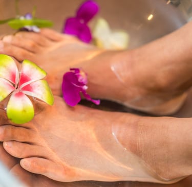 Feet bathing in a bowl of water with flowers