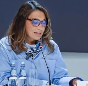 a woman in a blue shirt and glasses sitting at a table