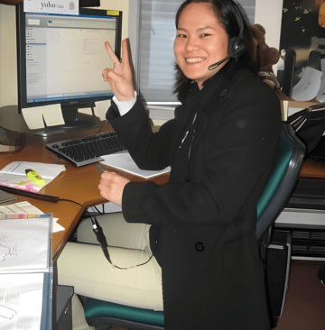 a woman sitting at a desk with a computer and a laptop