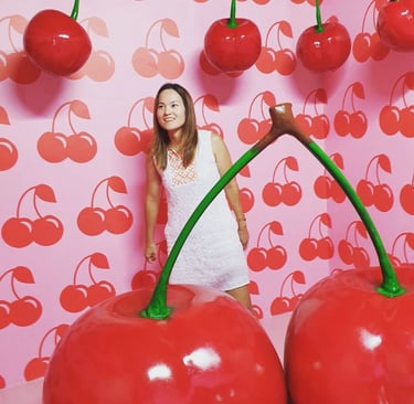 an asian woman standing in front of a wall with cherries