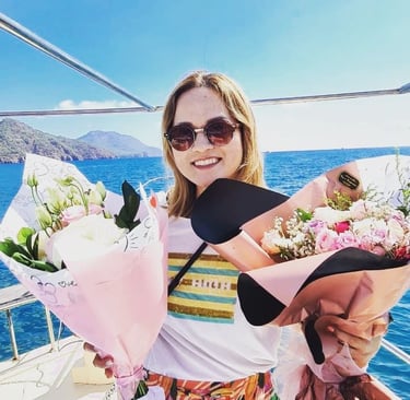 an asian woman holding a bunch of flowers on a boat