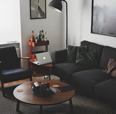 Modern living room with black leather sofa and laptop, illustrating accommodation options forstudent