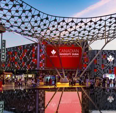 Canadian University Dubai entrance at dusk with large illuminated sign, highlighting the vibrant