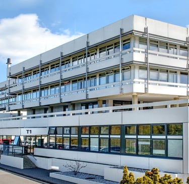 Max Planck Institute building with white exterior and windows, set against a blue sky with scattered