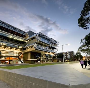 Monash University modern building with glass facade illuminated at dusk, representing academic excel