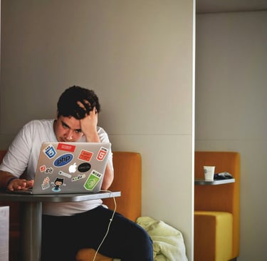 Stressed individual using a laptop at a table, symbolizing challenges in remote learning amid global