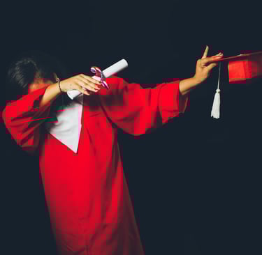 Indian student in red graduation gown celebrating academic success, holding a diploma and tassel