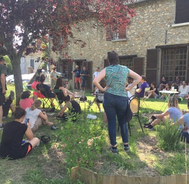a woman standing in a garden with people sitting around