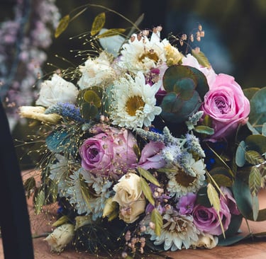Bunter Brautstrauß mit Rosen und Eukalyptus auf einem Holzstuhl. Hochzeitsfloristik-Foto: Just Perspectives.
