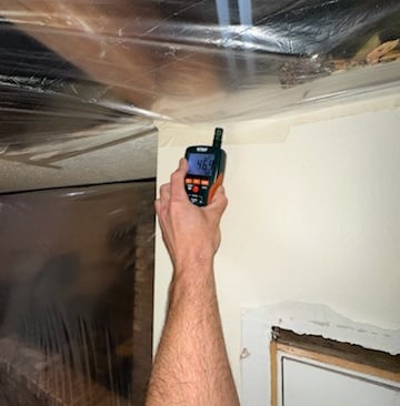 Moisture readings being taken on wall