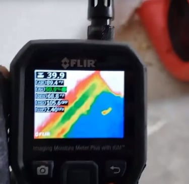 A FLIR moisture meter displays thermal imaging data for professional water damage restoration and leak detection.