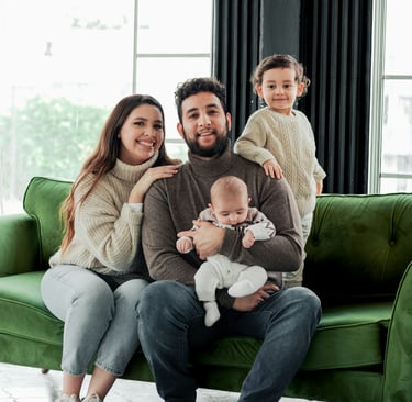 Happy family with two children posing on a green velvet sofa during a home lifestyle photoshoot.