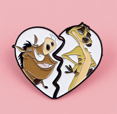 Two enamel pins featuring Timon and Pumbaa forming a broken heart shape on a pink background.