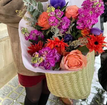 Bouquet de fleurs de saisons très coloré orange fuchsia bleu dans un panier pour partir livrer