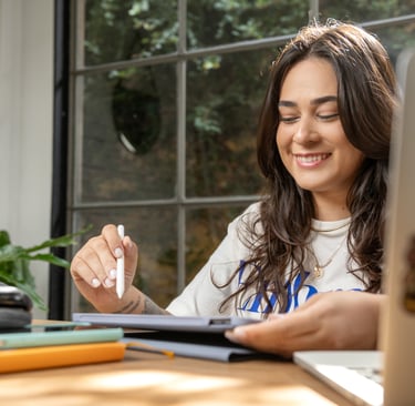 a woman sitting at a table with a pen and pencil