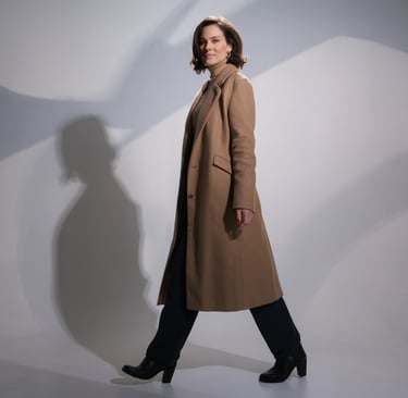 a woman in a coat and heels walking down a white floor
