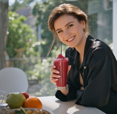 a woman holding a smoothie in front of a table