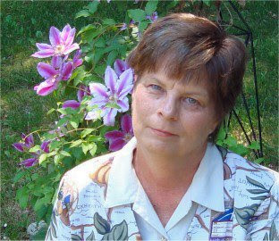 headshot of the artist, Diane Lalomia in front of Clematis growing in the garden