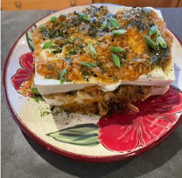 a plate with a slice of tofu and enoki mushrooms on it