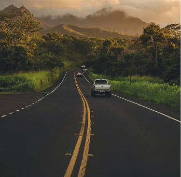 a car driving down a road with mountains in the background