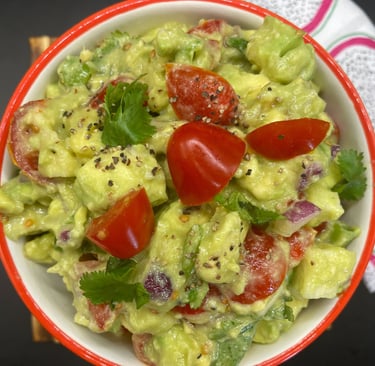 a bowl of guacamela with tomatoes and guacamole