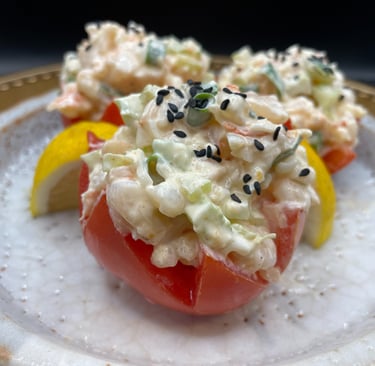 a plate with a crab salad stuffed in a tomato on it
