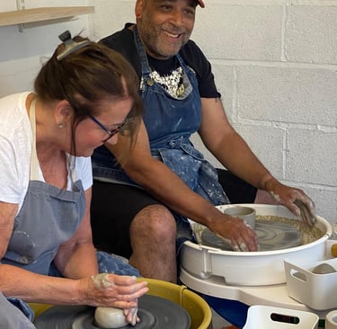 two people enjoying a pottery lesson on the potters wheel