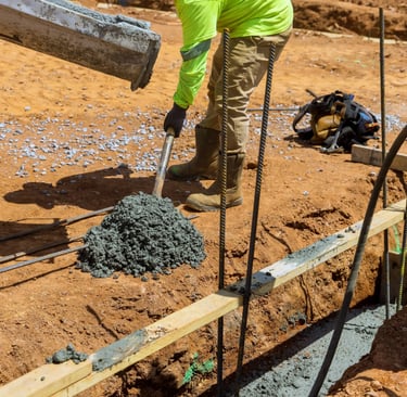 a man in a yellow jacket is pouring concrete into a concrete slab