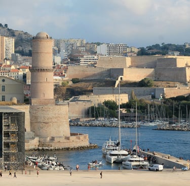 Panoramic view of Marseille Old Port featuring Fort Saint-Jean tower and the MuCEM museum building.