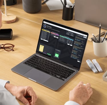 A person using a laptop with a data dashboard and CRM software on a wooden office desk.