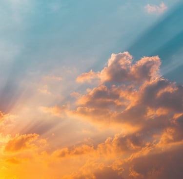 Golden sunbeams piercing through orange sunset clouds in a vibrant blue sky.