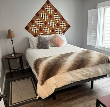 Cozy modern bedroom with a handmade quilt wall hanging and a faux fur throw on the bed.