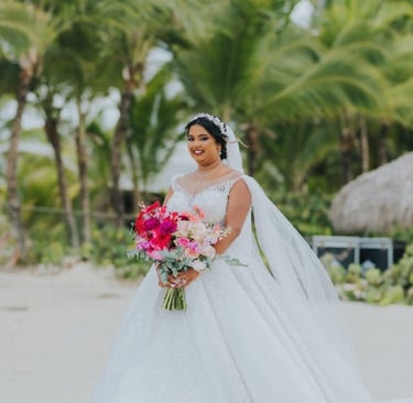 Beach bride in flowing gown holding colorful bouquet during tropical wedding