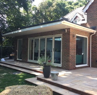 a bungalow house with bifold doors. there are 5 leaves on the doors and two white windows.