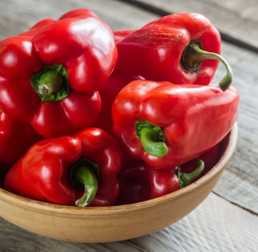 a bowl of red peppers on a wooden table