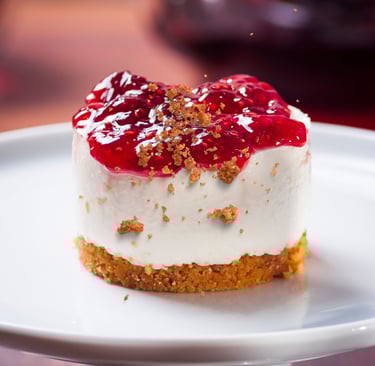 Mini cheesecake cups topped with fresh raspberries and a dusting of graham cracker crumbs