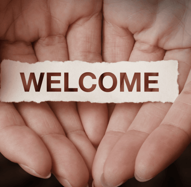 hands holding a piece of paper with the word welcome